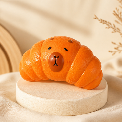 Orange Capybara Croissant Slow-Rising Squishy Toy on a cream display stand